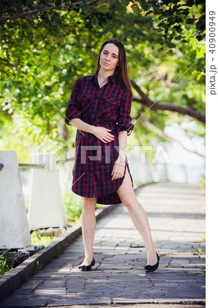 Beautiful, pretty woman in casual checkered dress walking at park outdoors. Street fashion style. Beautiful, pretty woman in casual checkered dress walking at park outdoors. Street fashion style. 40900949