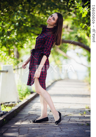 Beautiful, pretty woman in casual checkered dress walking at park outdoors. Street fashion style. Beautiful, pretty woman in casual checkered dress walking at park outdoors. Street fashion style. 40900961
