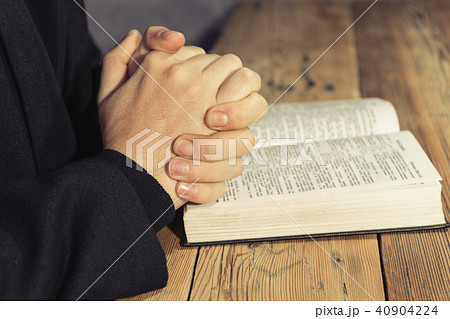 Man sitting at a old oak table reading Holy Bible Man sitting at a old oak table reading Holy Bible 40904224