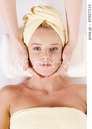 Young woman laying down and receiving face massage 40907314