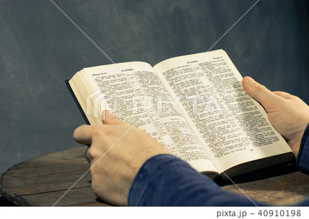 Young man sitting at a table reading Holy Bible 40910198
