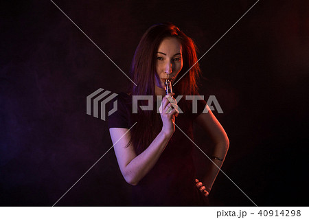 young woman smoking electronic cigarette on dark background young woman smoking electronic cigarette on dark background 40914298