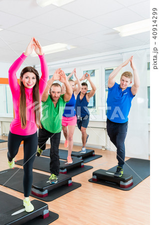 Men and women doing step-aerobics at gym Men and women doing step-aerobics at gym 40914299