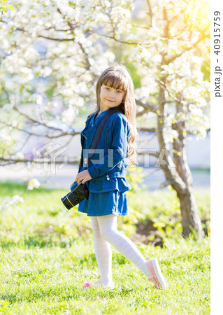 A beautiful little girl is holding a camera in her hands. 40915759