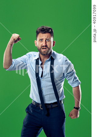 The young emotional angry man screaming on green studio background 40917099