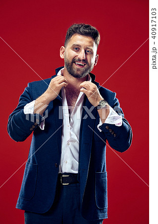 The happy business man standing and smiling against red background. The happy business man standing and smiling against red background. 40917103