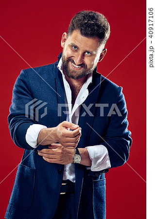 The happy business man standing and smiling against red background. The happy business man standing and smiling against red background. 40917106