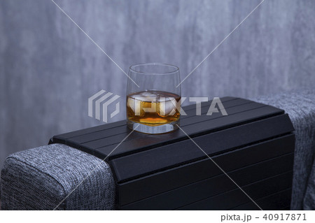 a glass of whiskey alcohol is on the arm of the sofa 40917871
