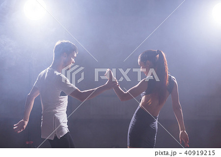 Skillful dancers performing in the dark room under the concert light and smoke. Sensual couple 40919215
