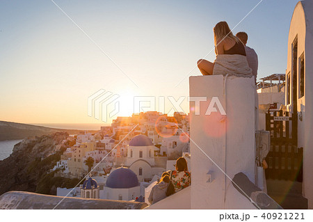 Couple watching sunrise and taking vacation photos at Santorini island, Greece. 40921221