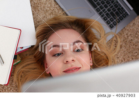 young beautiful woman lie on floor have a lot of work hold tablet in arms young beautiful woman lie on floor have a lot of work hold tablet in arms 40927903