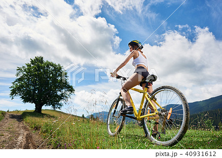 Young happy woman riding bicycle in the mountains at summer day Young happy woman riding bicycle in the mountains at summer day 40931612