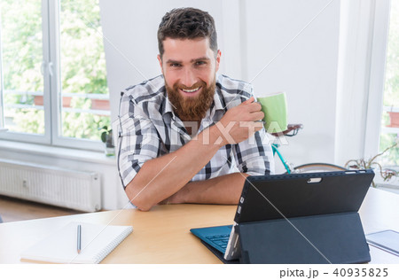 Portrait of a confident self-employed young man sitting at desk  40935825