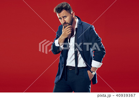 Suspiciont. Doubtful pensive man with thoughtful expression making choice against red background 40939367