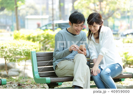 公園でスマホを見るカップルの写真素材