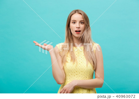 Woman surprise showing product. Beautiful girl with curly hairstyle pointing to the side. Presenting 40963072