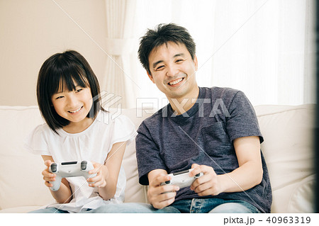 テレビゲームで遊ぶ親子 父親と小学生の娘の写真素材