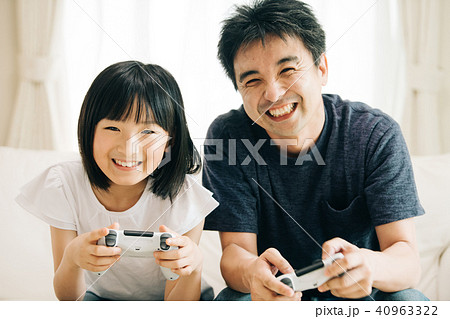 テレビゲームで遊ぶ親子 父親と小学生の娘の写真素材