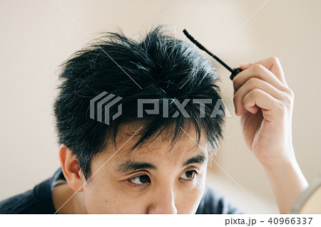 ヘアマスカラで白髪を染める中年男性の写真素材