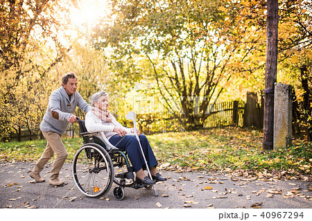Senior man and woman in wheelchair in autumn nature. Senior man and woman in wheelchair in autumn nature. 40967294