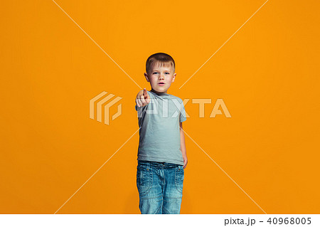 The happy teen boy pointing to you, half length closeup portrait on orange background. 40968005