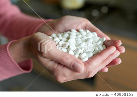 Woman's holding cupped hand full of pills 40968158