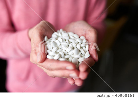 Woman's holding cupped hand full of pills 40968161