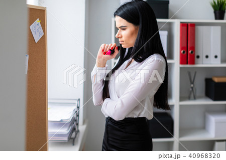 A young girl holds a marker in her hand and stands near the board with stickers. A young girl holds a marker in her hand and stands near the board with stickers. 40968320