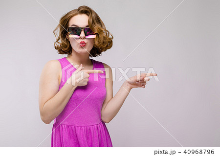 Charming young girl in pink dress on gray background. Cheerful girl in square glasses. The girl 40968796