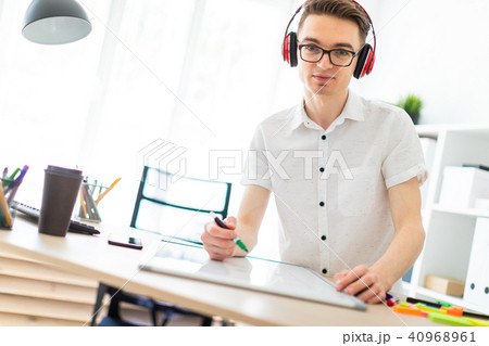A young man with glasses and headphones draws a marker on the magnetic board. A young man with glasses and headphones draws a marker on the magnetic board. 40968961