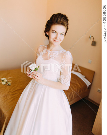 Lovely smiling bride in the long white dress holding the mini-bouquet. 40969006