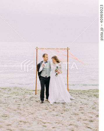 Happy newlyweds walking on the beach during the sunset. 40969023