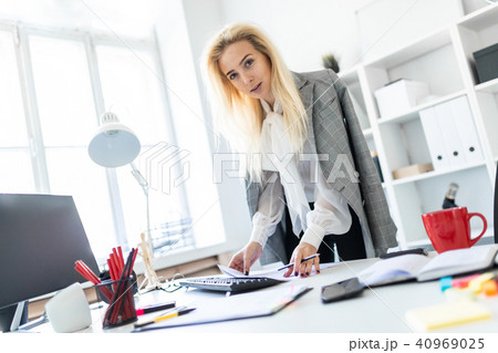 A young girl stands in the office, hands on the table. A young girl stands in the office, hands on the table. 40969025