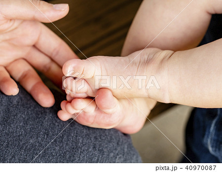 赤ちゃんが足を組んでいる そしてお母さんの手の写真素材