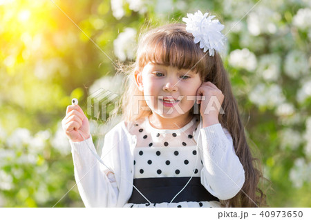 A girl in a white dress listens to music through small audio headphones. A girl in a white dress listens to music through small audio headphones. 40973650