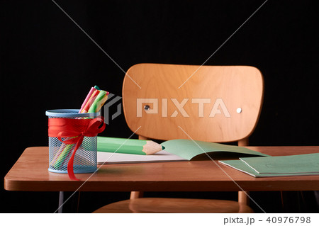 A glass with colored pens on a wooden table 40976798
