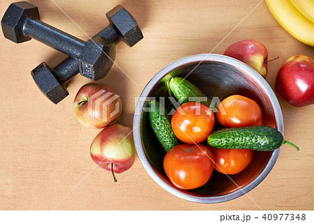 Fruits, vegetables and dumbbells on table Fruits, vegetables and dumbbells on table 40977348