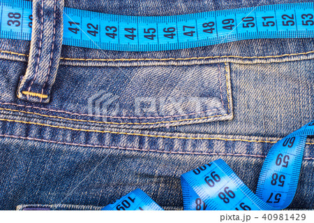 Concept of healthy lifestyle, weight loss. Jeans with measuring tape 40981429