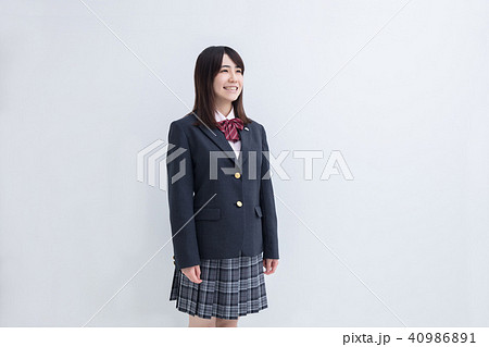 白い背景で立っている冬服の女子高校生の写真素材