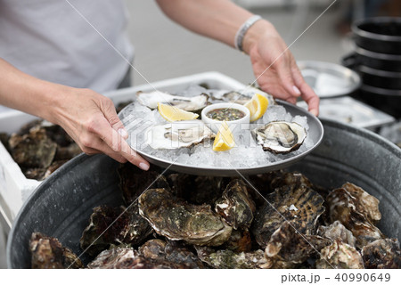 Close Up of Server with Tray of Fresh Shucked Oysters with Lemon Wedges Served as Appetizer Close Up of Server with Tray of Fresh Shucked Oysters with Lemon Wedges Served as Appetizer 40990649