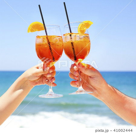 Two cocktail glasses in hands on sea background 41002444