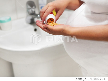 Pregnant woman in bath room taking pills 41002794