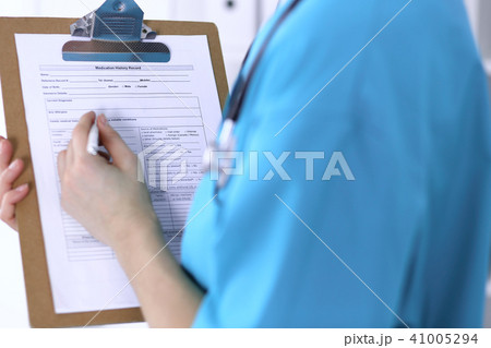 Female doctor filling up medical form on clipboard closeup. Physician finish up examining hi Female doctor filling up medical form on clipboard closeup. Physician finish up examining hi 41005294