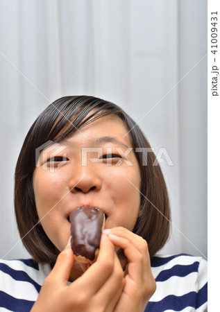エクレアを美味しそうに食べる女の子 41009431