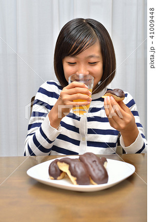 エクレアを美味しそうに食べる女の子の写真素材 エクレアを美味しそうに食べる女の子の写真素材