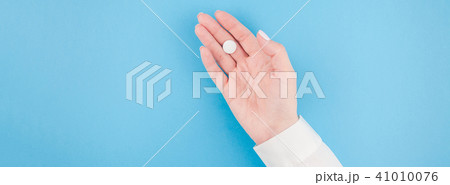 Female hand holding a white pill Female hand holding a white pill 41010076