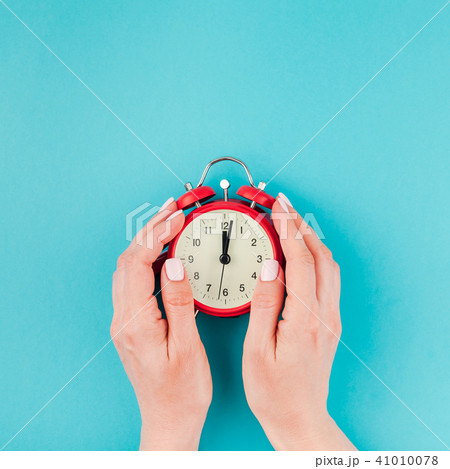 Woman hands holding the red vintage alarm clock Woman hands holding the red vintage alarm clock 41010078