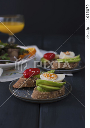 Toasts with avocado, yatsom and cherry tomatoes, on a black wooden background. Juice and delicious 41016079