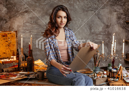 The young attractive artist in the course of drawing looks forward at an image with which she paints The young attractive artist in the course of drawing looks forward at an image with which she paints 41016638