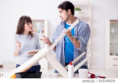 Wife helping husband to repair broken chair at home 41018028